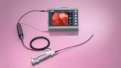 A medical endoscopic device with a white handle and a flexible black cable is connected to a monitor displaying an internal view of the body, set against a pink background.